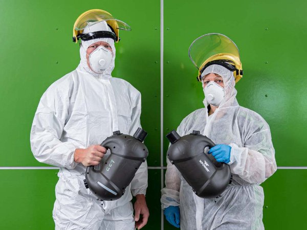 Smiling Green Clean Team staff member standing against a green wall, taking a short break during a biohazard clean in Bendigo, Central Victoria.