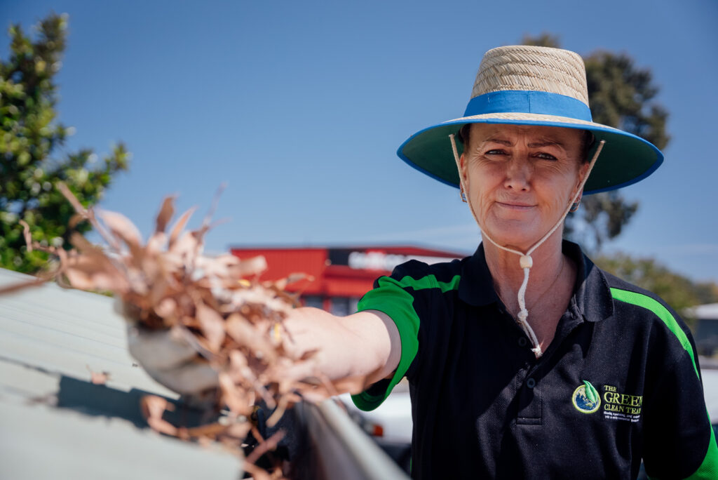 Green Clean Team staff member clearing leaves from a gutter on a roof in Bendigo, Central Victoria.