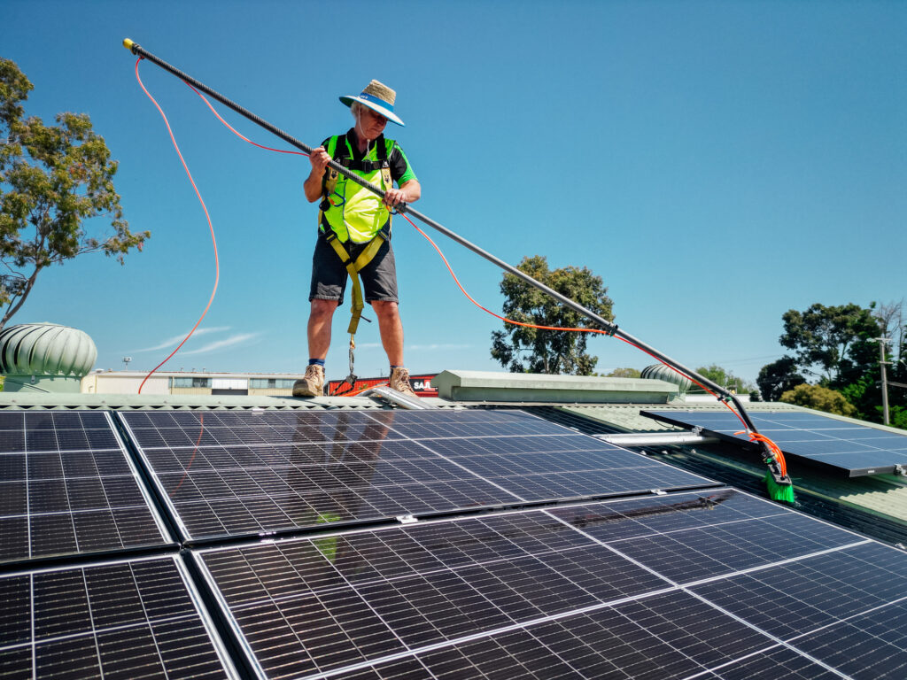 A Green Clean Team staff member in safety gear cleaning solar panels on a roof in Bendigo, Central Victoria