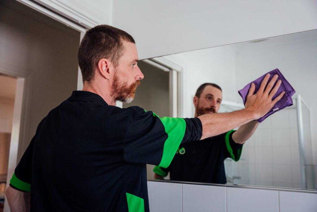 Green Clean Team member cleaning a bathroom mirror in a Central Victorian home during an eco-friendly clean