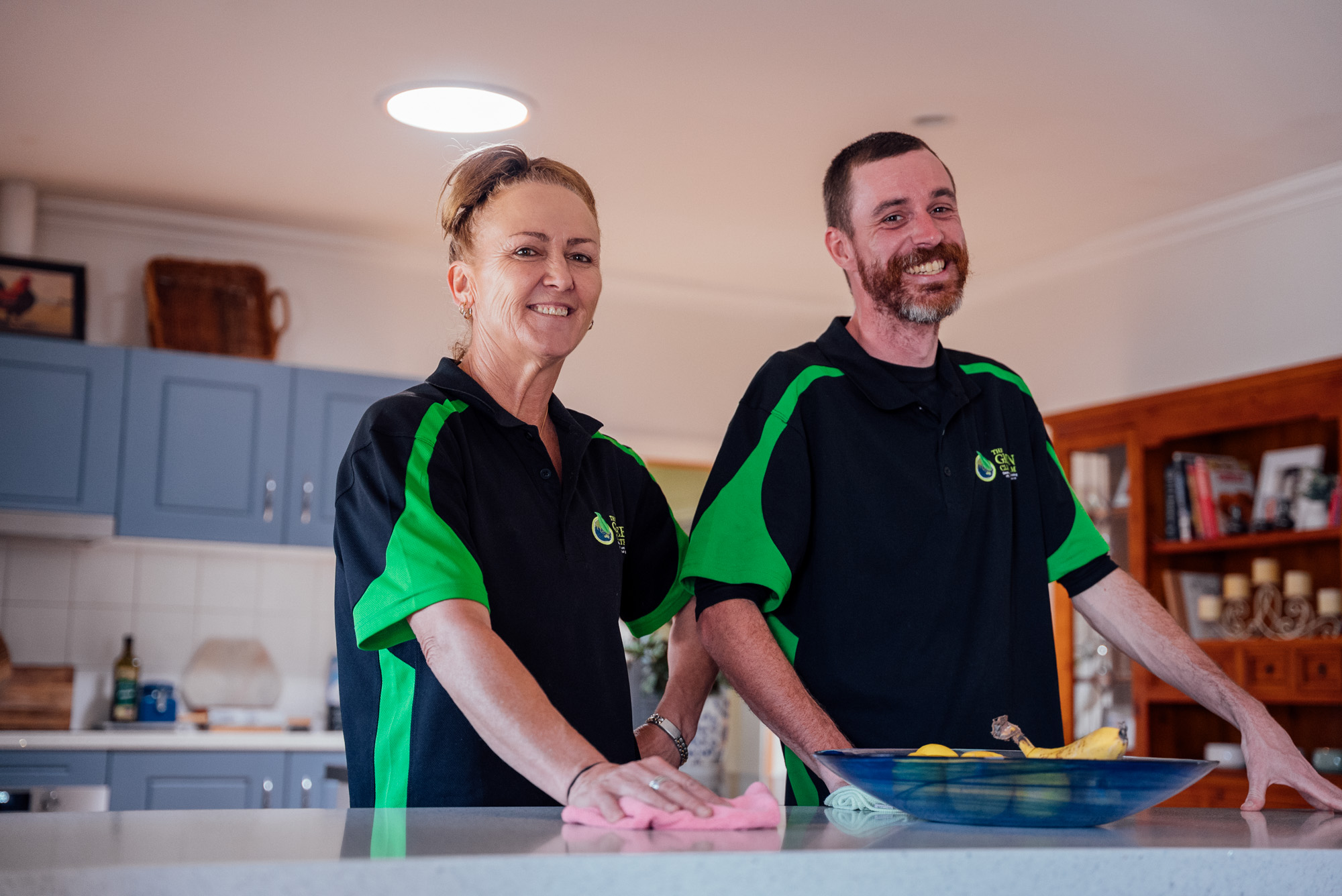 Two Green Clean Team technicians cleaning a bench and smiling in Central Victoria home